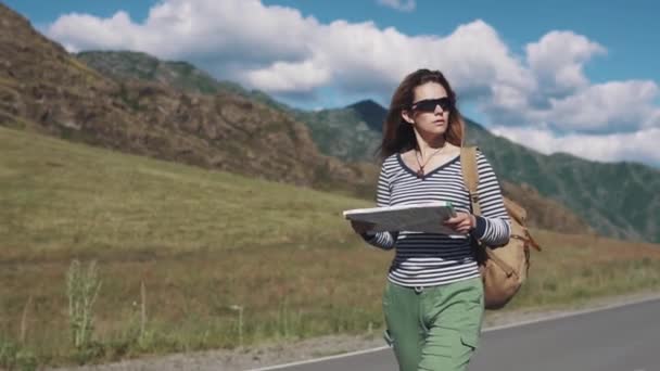 Portret z bliska kobieta podróżnik. turysta dziewczyna z papierowej mapy w jej rękach jest chodzenie wzdłuż autostrady — Wideo stockowe