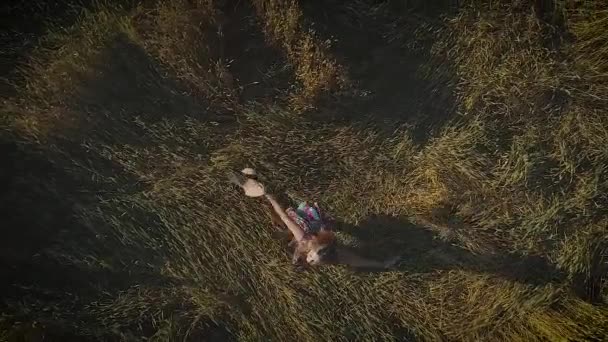 Aerial. attractive girl is spinning in a meadow, holding a straw hat. view from above. slow motion — Stock Video