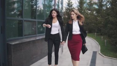 iş adamları office Merkezi'ne gidin. iş takım elbiseli iki genç kadın. kadın saate görünüyor