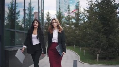 iş modern bir bina arka plan üzerinde iki genç kadın portresi. iş kadınları güvenle iş merkezi yürümek
