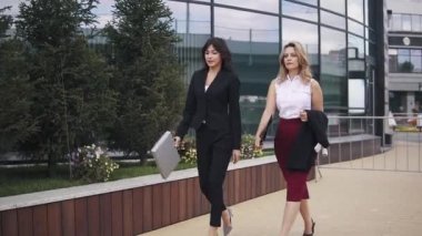 bir iş merkezinin arka plan üzerinde modern iş kadını. iki genç kız kağıtları için klasörler ile karşılamak için acele