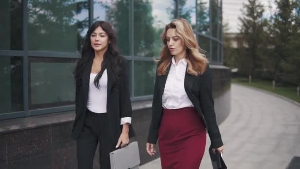 Deux femmes d'affaires en procès vont dans le contexte du centre d'affaires. la fille porte une mallette pour les papiers . — Video