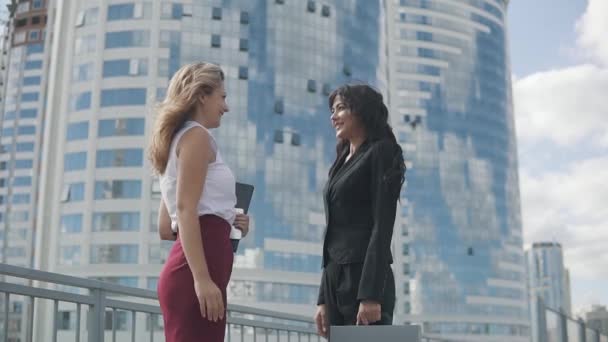 Satisfied business women give each other high five and smile happily. portrait of girls in strict suits against the backdrop of a business center — Stock Video