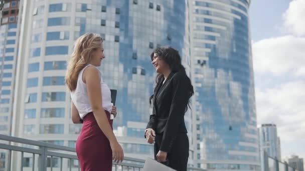 Concept of success in business relations. satisfied business women give each other five and smile happily. portrait of girls in strict suits against the backdrop of a business center — Stock Video