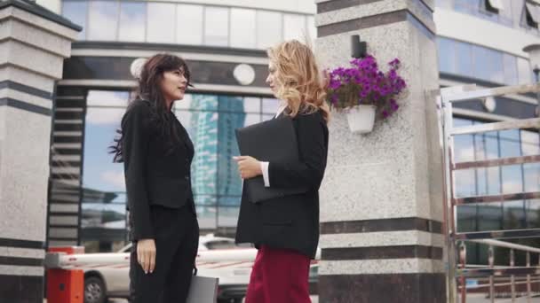 Reunión de socios de negocios al aire libre. dos mujeres de negocios en trajes estrictos están hablando — Vídeo de stock