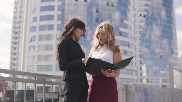 Reunión informal de socios comerciales en el contexto del centro de negocios. dos mujeres de negocios en trajes formales hablando al aire libre — Vídeo de stock