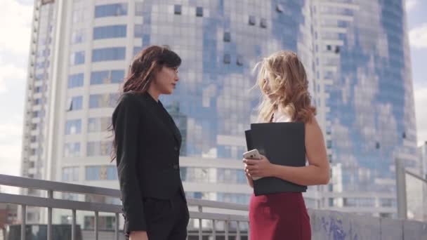 Informal meeting of business partners on the background of the business center. two business women in formal suits talking outdoor — Stock Video