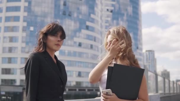 Zakelijke partners spreken voor onderweg. twee zakelijke vrouwen in formele pakken op de achtergrond van het business center — Stockvideo