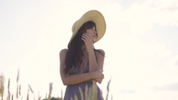 Портрет девушки в соломенной шляпе на пшеничном поле. молодая привлекательная женщина в деревенском платье — стоковое видео