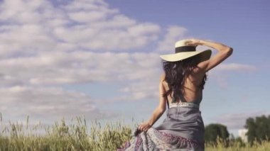 şirin ve kaygısız bir kız alanın karşısındaki çalışır ve hasır şapkasını atar. Mutlu bir genç kadının portresi. Arkadan görünüm. ağır çekim