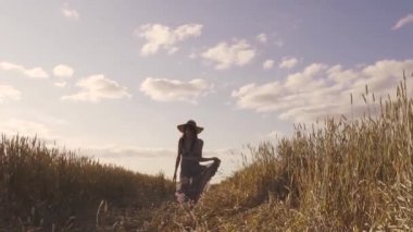 neşeli kaygısız kız buğday alanı çalışır ve hasır şapka kadar atar. Neşeli ve kaygısız yaz kavramı. Genç kadın kamera için çalışır. ağır çekim