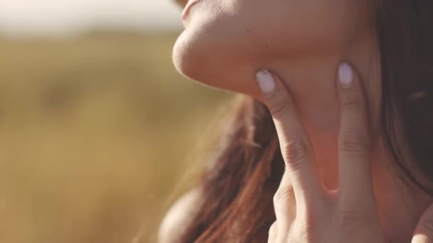 Söt ung flicka vidrör halsen. Ung kvinna åtnjuter en varm sommardag i fältet — Stockvideo