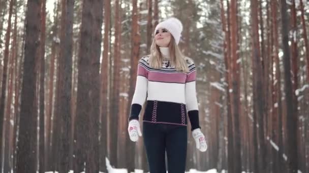 Joven hermosa chica en un suéter y manoplas está caminando a través del bosque y sonriendo — Vídeos de Stock