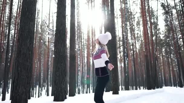 Девушка в зимнем лесу кружится и радуется лучам солнца — стоковое видео