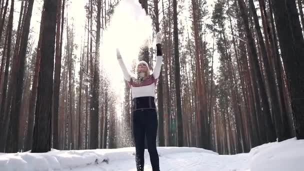 Девушка бросает снег и радостно кружится, наслаждаясь солнечным зимним днем. замедленное движение — стоковое видео