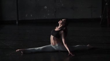 pratik yoga geniş bir karanlık salonda yalnız kız esnek ve plastik. ağır çekim