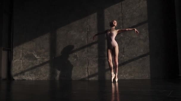 Kecses és vonzó fiatal balerina forog lábujjhegyen, a pointe cipők sötét háttér előtt a stúdióban. Balett-táncos bodysuits. lassú mozgás — Stock videók