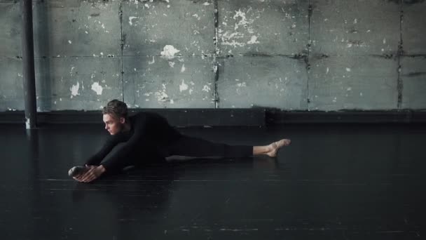 Балетный танцор делает растяжку сидя на бечевке на полу — стоковое видео