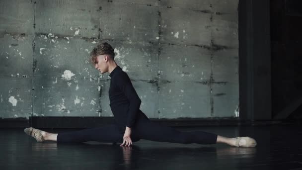 Férfi balett-táncos, zsineg, a padlón ül, és ezzel a nyújtás — Stock videók