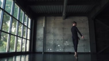 Bale dansçısı. Genç adam stüdyo karanlık bir arka plan üzerinde incelikle dans