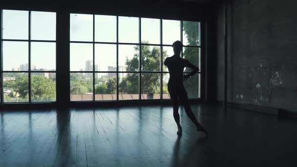 Силует балетної танцівниці на фоні вікна. чоловік елегантно і красиво танцює класичний балет в студії. повільний рух — стокове відео