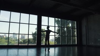 büyük bir pencere arka plan üzerinde bir balerin silüeti. dansçı sessizce döner ve incelikle taşır. ağır çekim