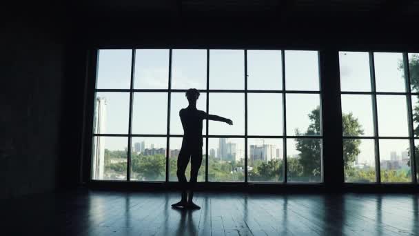 Silhouet van een ballet danseres Man wervelende op zijn tenen tegen de achtergrond van een groot raam. Slow motion — Stockvideo