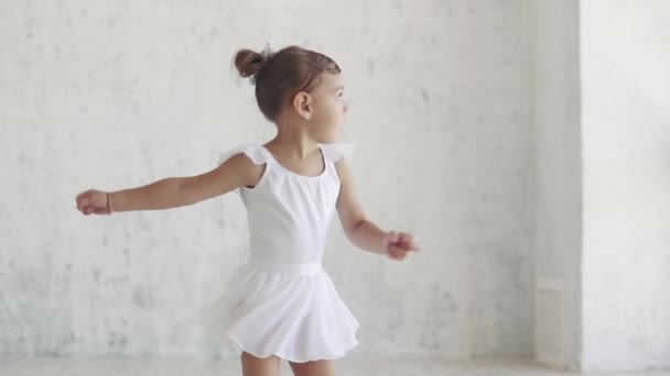Porträt einer kleinen Balletttänzerin in einem klassischen Tutu, das im Studio vor hellem Hintergrund wirbelt. Zeitlupe — Stockvideo