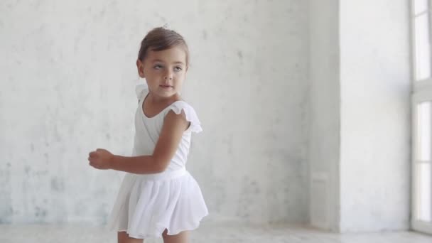 Retrato de una niña bailarina de ballet en un tutú clásico que baila sobre un fondo claro en el estudio. Movimiento lento — Vídeo de stock