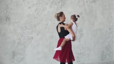 Genç bir kadın küçük bir çocuk onun kollarında tutar ve çevresinde onunla bir bale sınıfta fırtınası