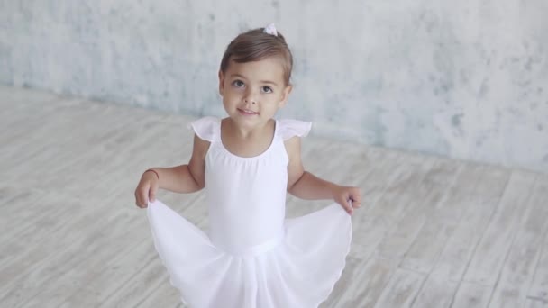 Portrait en gros plan d'une belle petite ballerine dans un tutu blanc. l'enfant regarde la caméra — Video