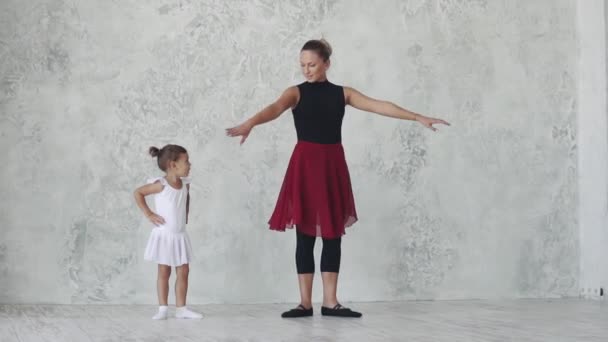 Profesora de ballet enseña una pequeña bailarina en el estudio. la chica es coreógrafa en una clase de ballet con un pequeño estudiante — Vídeo de stock