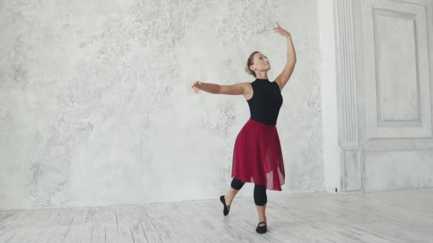 Uma bailarina em bodysuits pretos e uma saia vermelha dança em uma classe de balé. câmara lenta — Vídeo de Stock