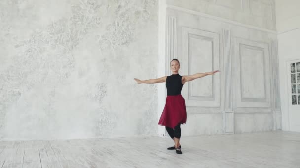 Danseuse de ballet en body noir et jupe rouge danse sur un fond clair. La ballerine se déplace gracieusement et élégamment. au ralenti — Video