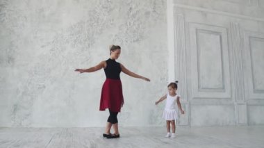 küçük bir kız Balerin Bale sınıfta arkasında hareketleri tekrar dener. ağır çekim