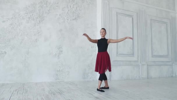 Uma bailarina em bodysuits pretos e uma saia vermelha dança em uma classe de balé. câmara lenta — Vídeo de Stock