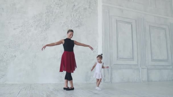 A small child in the classroom for ballet. a little girl in a tutu repeats the movements of the teacher. slow motion — Stock Video