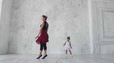 küçük bir kız Balerin Bale sınıfta arkasında hareketleri tekrar dener. ağır çekim