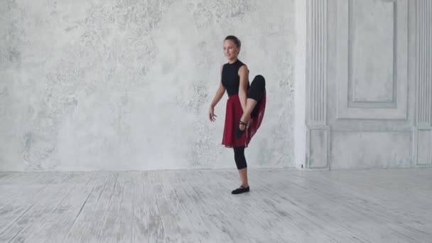 Baletka v černých kombinézách a červenou sukni tančí na světlém pozadí. Baletka se pohybuje vznešeně a elegantně. Zpomalený pohyb — Stock video