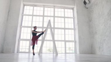 Balerin siyah gömlek ve kırmızı etek Studio büyük bir ışık pencere arka plan üzerinde bir esneme yapar. ağır çekim