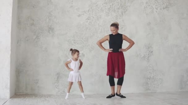 Μια μικρή μπαλαρίνα επαναλαμβάνει τις κινήσεις του δασκάλου και άλματα. μάθημα μπαλέτου στο στούντιο — Αρχείο Βίντεο