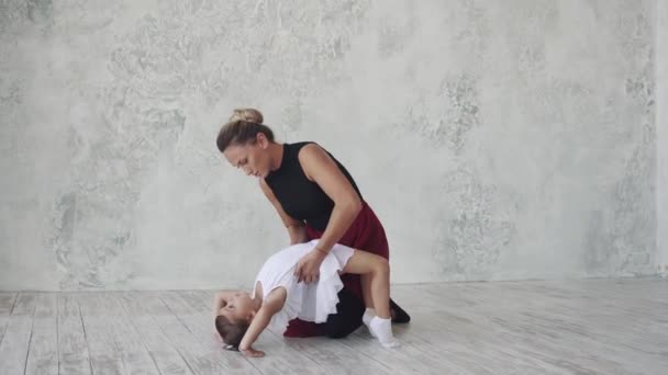 Uma pequena bailarina está a estudar ballet com a professora. A coreógrafa e o seu pequeno aluno — Vídeo de Stock