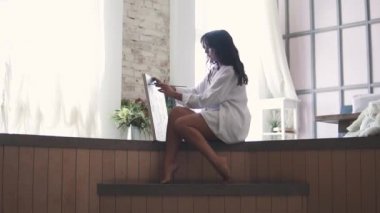 Kız ressam beyaz gömlekli katta oturan ev resmini yazıyor