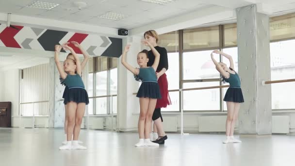 Un insegnante di balletto insegna piccole ballerine in una classe di balletto. insegnante corregge studente — Video Stock