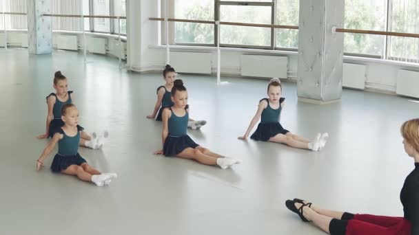 Koreografi lektion i studion. barn sitta på golvet och upprepa rörelserna av läraren — Stockvideo