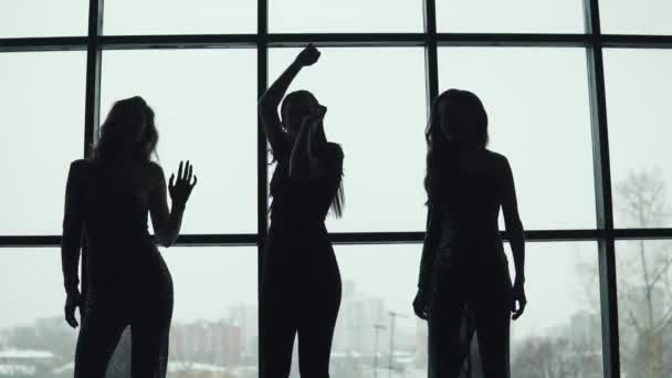 Silhuetas de meninas dançando no fundo de uma grande janela — Vídeo de Stock