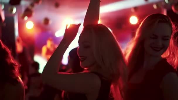 Amis dansant sous les projecteurs dans une discothèque dans une boîte de nuit. filles dansant dans une foule de personnes — Video