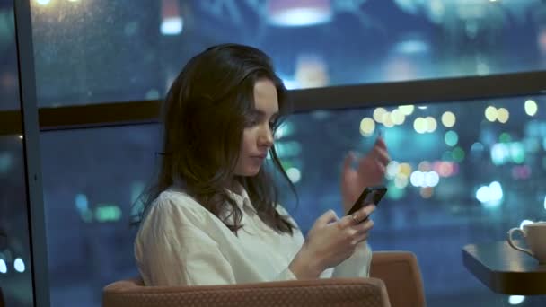 Νεαρή Κοπέλα Είναι Πληκτρολογώντας Ένα Μήνυμα Στο Smartphone Ενώ Κάθεται — Αρχείο Βίντεο