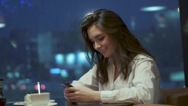 Egy fiatal lány mosolyog, és a nevet egy mobil telefon üzenet küldése során — Stock videók