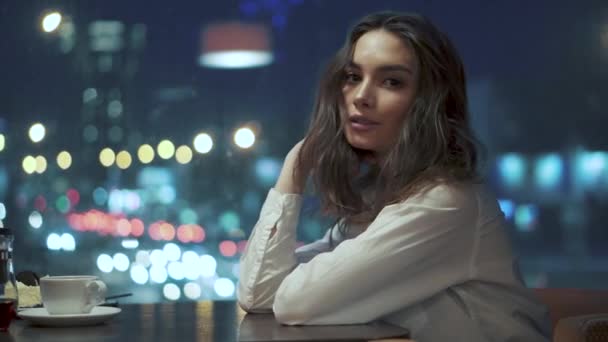 Retrato de una linda joven con una hermosa sonrisa en un café nocturno — Vídeos de Stock